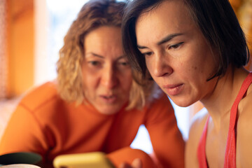 woman showing her friend a picture on a smartphone