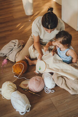 Woman with her child sitting on the floor embroidering, using scissors, cuts threads. The concept...