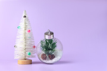 A beautiful white fir tree and a large glass Christmas ball on a purple background, we celebrate the new year