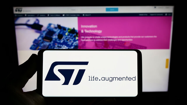 Stuttgart, Germany - 10-30-2022: Person holding smartphone with logo of semiconductor company STMicroelectronics N.V. on screen in front of website. Focus on phone display.