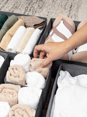 Concept of order in house. Dark gray closet organizers drawer divider. Woman folds towels closeup