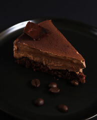 Part of a chocolate dessert cake on a plate under dark lighting. Shallow depth of field