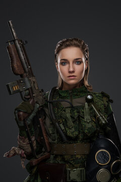 Portrait of apocalyptic female survivor holding rifle dressed in camouflage uniform.