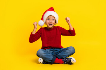 Full body photo of charming little boy raise fists excited santa claus helper wear trendy red...
