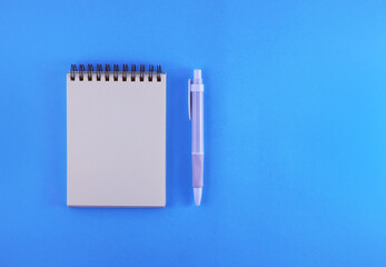 Notepad for planning. Blank notepad and pen on a blue background. View from above.