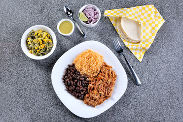 Delicious dish served of cochinita pibil, beans and rice on gray background
