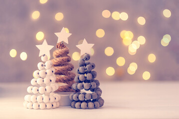 Obraz premium Three Christmas trees on table with bokeh lights.