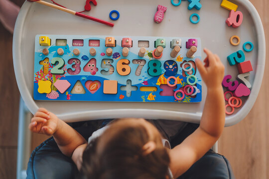 Baby girl playing, learning numbers, counting with help of a wooden math educational toy. Early development. Leisure concept. Educational toys. Education