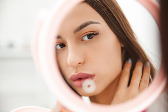 Portrait of a young brunette looking in the mirror. the reflection of a woman in the mirror. the girl admires her reflection in the mirror