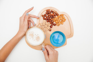 breakfast is served on a wooden tray. nuts and tea on a wooden tray on a white table