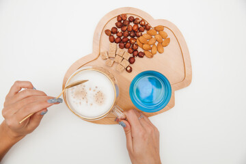 breakfast is served on a wooden tray. nuts and tea on a wooden tray on a white table