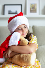 Caucasian little girl hugging teddy bear. Christmas time at home.
