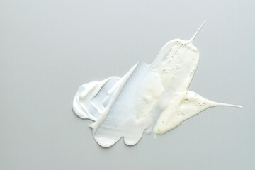 Beauty skin care product textures on gray background. Face cream, exfoliation scrub and cleancing foam smears.