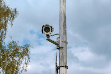 Frontansicht einer im Freien angebrachten, wetterfesten Überwachungskamera an einem verwitterten,...