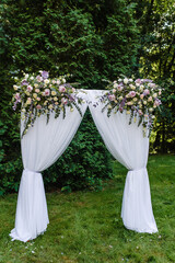wedding rectangular arch at an outdoor ceremony with pink and white roses against a background of greenery