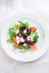 Salad with boiled beetroot, grapefruit, arugula and cream cheese. Beetroot slices with green salad, top view