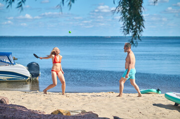 A couple playing tennis on the beach and looking excited