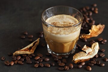 Mushroom coffee in a glass, coffee beans and dry mushrooms on a dark background. Selective focus