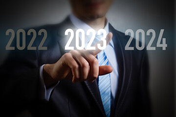 Finger pressing blue start 2023 button on virtual interface on gray background with copy space for text. Concept of new year. Businessman pressing 2023 start up business. Beginning of New Year 2023.
