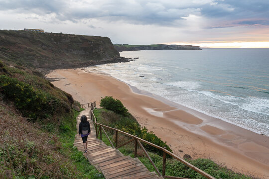 A woman goes down to Locos Beach at sunset. Suances, Cantabria