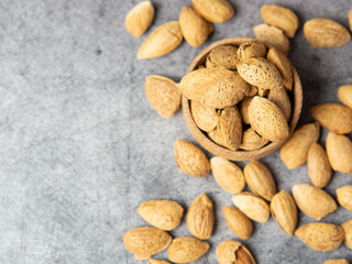 Obraz premium shelled almonds on a dark stone table with a wooden spoon and a bowl. Almonds in a wooden bowl.