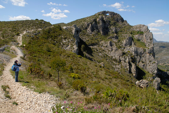 Woman hiker on mountain trail to the La Forada rock arch, Vall de Gallinera, Alicante Province, Spain