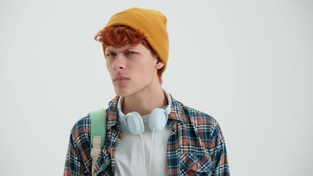 Angry red haired man wearing hat saying no at the camera in the white studio