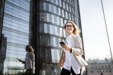 A woman with glasses is a marketing expert working in an office. Uses a phone device in his hands,...