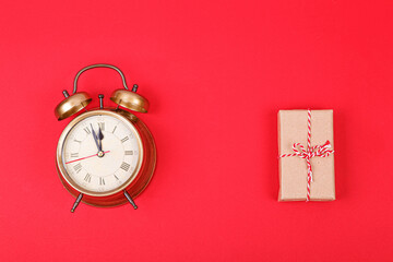 New Year's clock in gold color with a gift on a red background