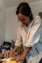 young latin woman, in her own painting studio, creates paintings different artistic techniques