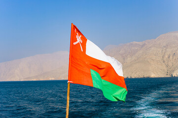 Oman Flag on a boat with sea and mountain backgrounds 