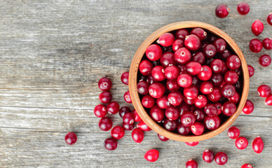 fresh cranberries in a wooden plate on the table, top view