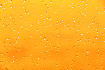 Yellow background with drops on a glass window. Beer drink close-up. Warm wet texture. Condensate. Raindrops flow down. Abstract textured background. Surface in droplets. Bright color backdrop