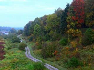 Autumn landscape in the morning. Country road along the river and forest. Kuldiga, Latvia.