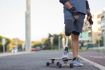 Close-up of man with prosthetic leg and skateboard. Strong person with disability in casual clothes...