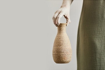 Minimal concept shot of female artist holding handmade ceramics, copy space