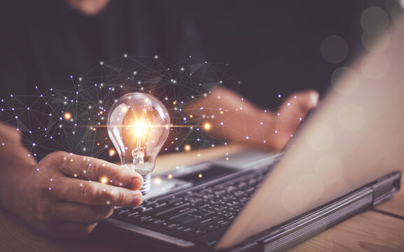 New business idea creativity concept, Businessman hand holding light bulb and using laptop computer for online network, Innovation and inspiration for business administration, Network connection.