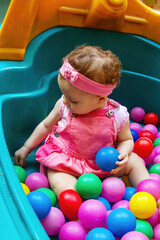 Obraz premium Baby girl playing in colorful polka dot pool in ball bath