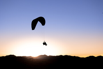 Silhouette of a Paraglider and Mountains Against Cloudless Sunset