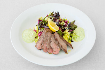 Vegetable steak salad with avocado dressing and lemon