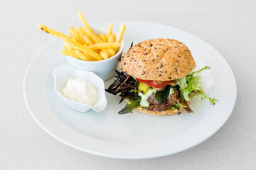 Delicious hamburger with vegetables, fries and dressing