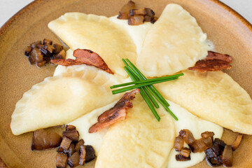 Filled sheep cheese pirohy dish served with bacon and fresh chive