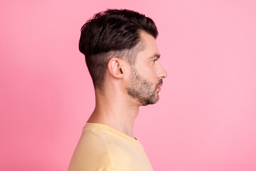 Fototapeta premium Side profile photo of serious positive guy with brunet hairstyle dressed yellow t-shirt look empty space isolated on pink color background
