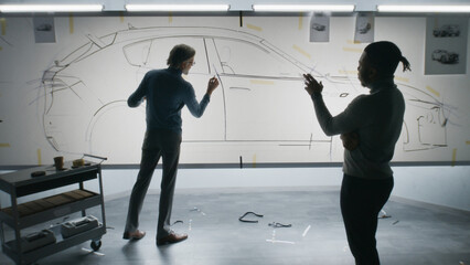 Two diverse automotive male designers discussing sketch, drawing with marker, developing futuristic...