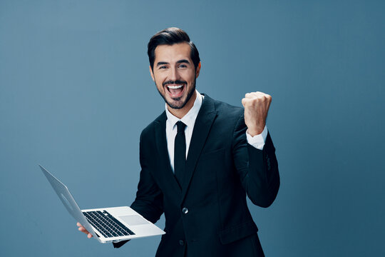 Man business stares at laptop and works online via internet in business suit video call happy smile with teeth fist bump happiness on blue background copy place