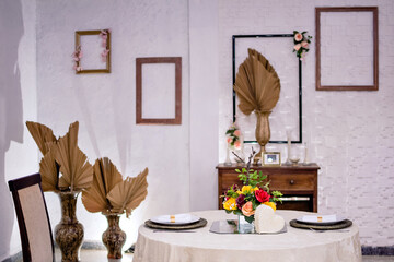 a dining table with white porcelain plates, cutlery and a vase with colorful flowers