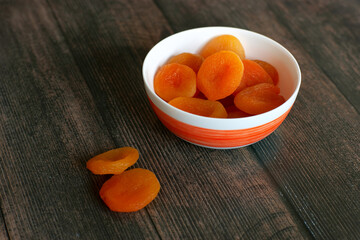 Dried apricots in a cup on a wooden background. Dried apricots for a healthy diet. Fruits in a cup close-up.