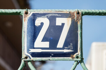 Weathered grunge square metal enameled plate of number of street address with number 27