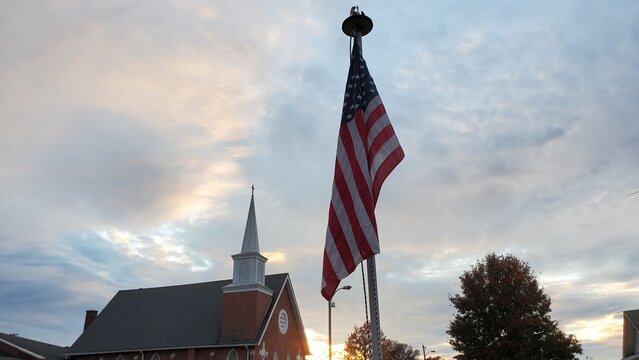 American flag with church behind it during sunset