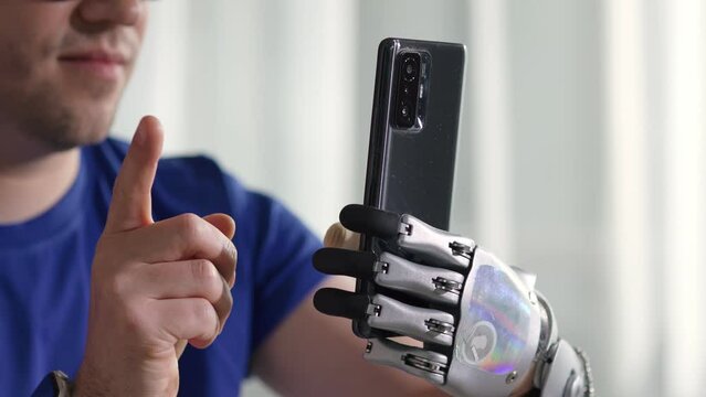 Close up of Happy young man with modern bionic arm use mobile phone reading news 